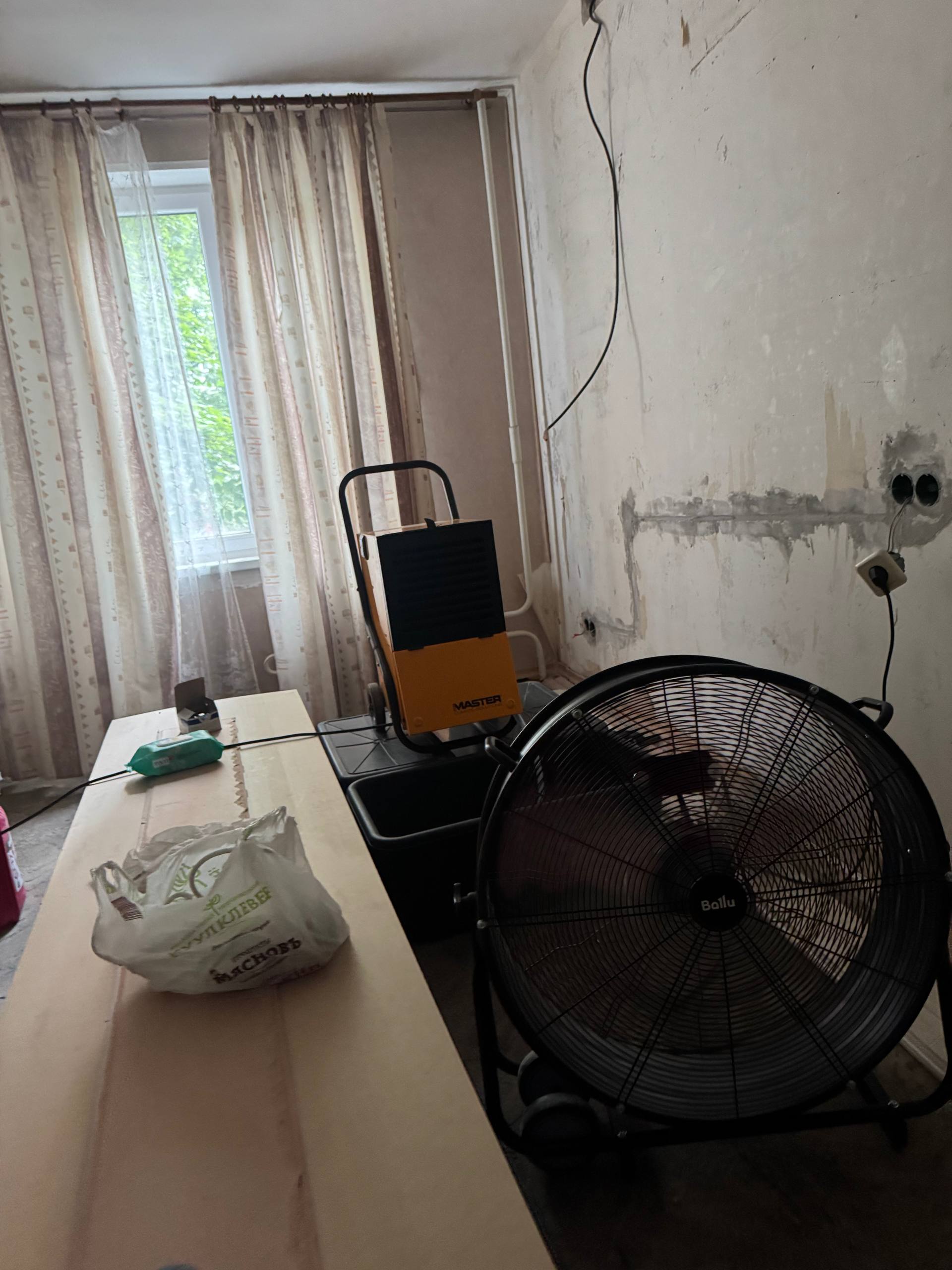 Напольный вентилятор рядом с осушителем в комнате